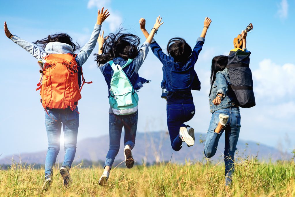 Trekking holiday concept.Four women are trekking in the mountains with backpack,tent,hiking equipment.