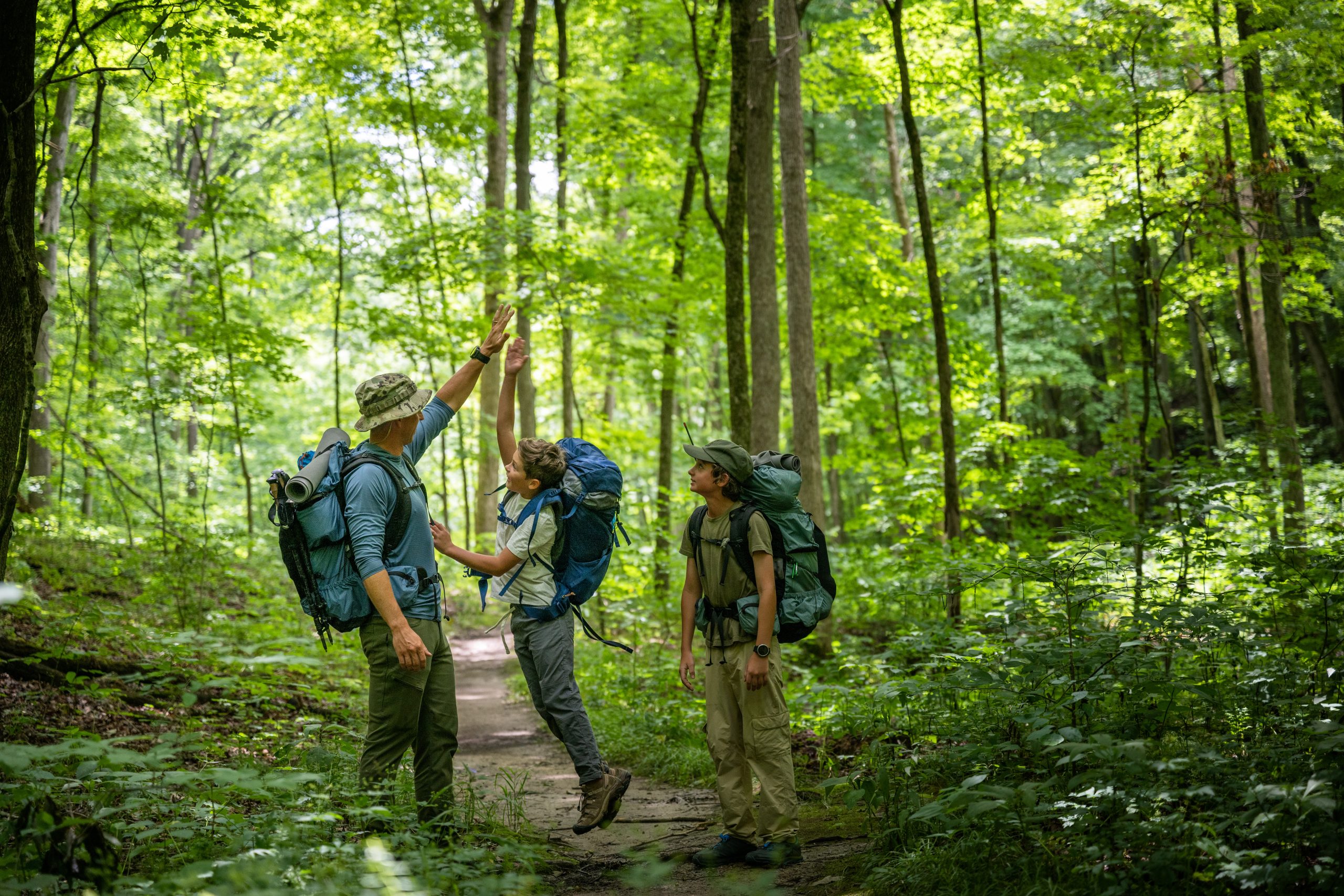 Air Force service member heads out on a hike with his sons on  a backpacking trip.